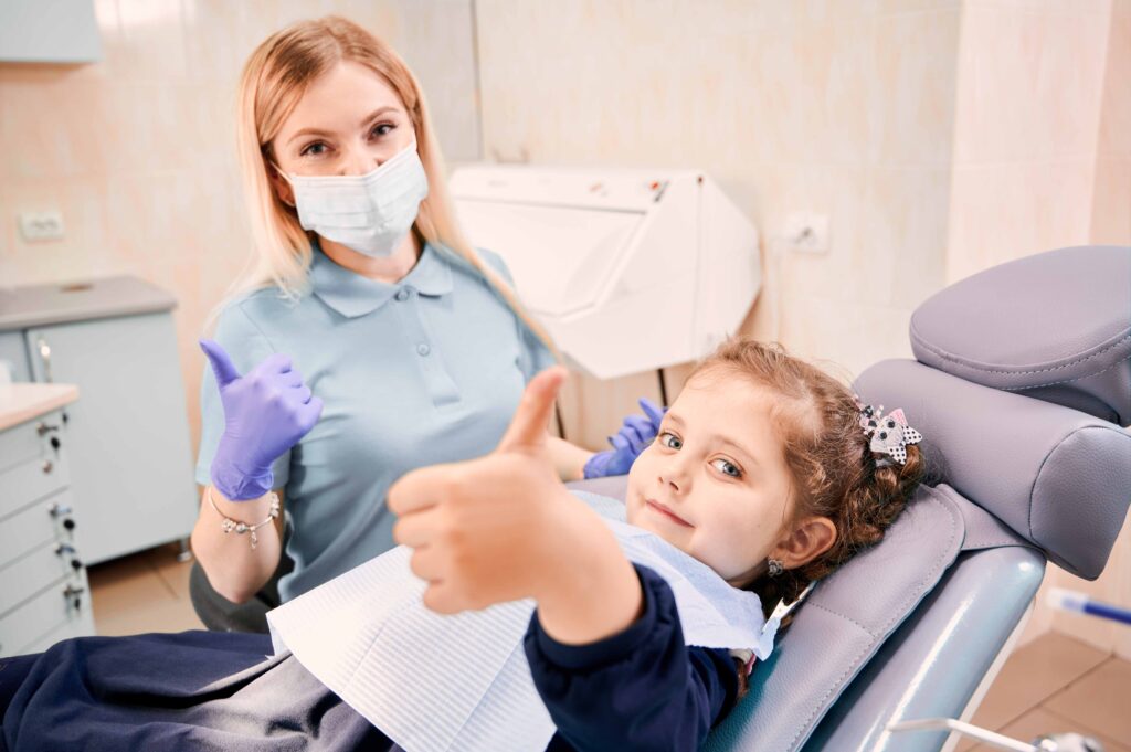 歯科の椅子に座る女の子と、その横にいる女性歯科医師