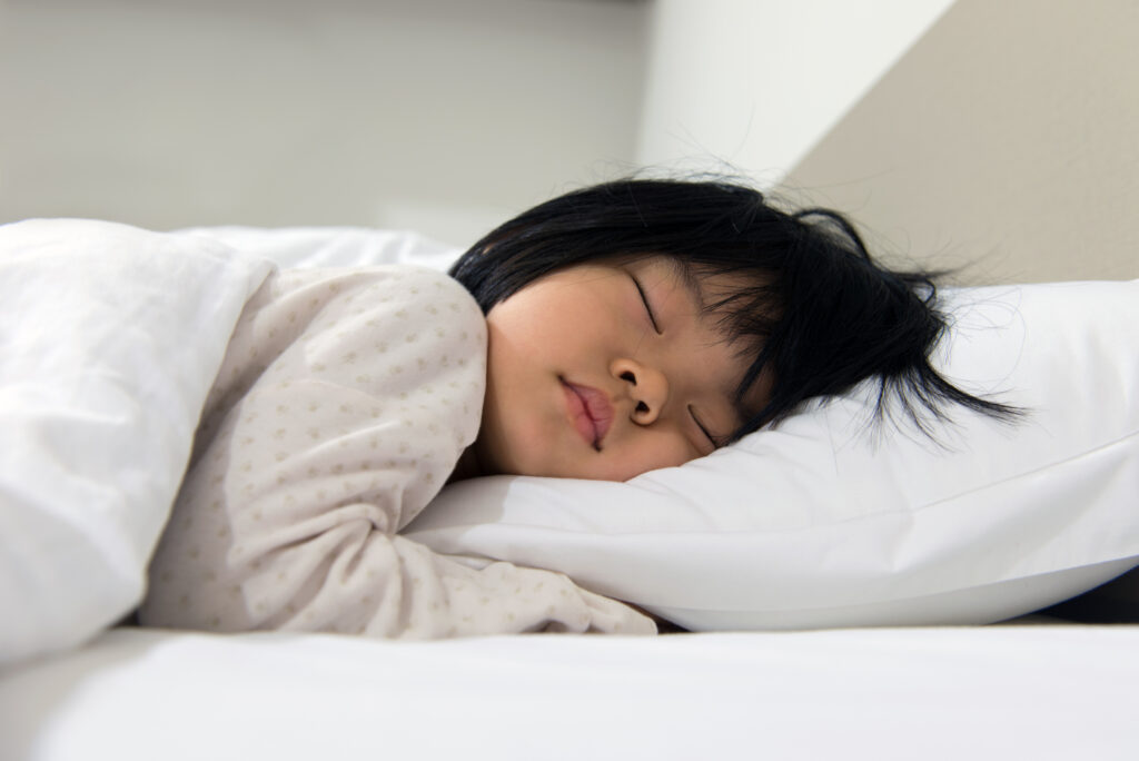 ベッドで眠るアジア系の女の子