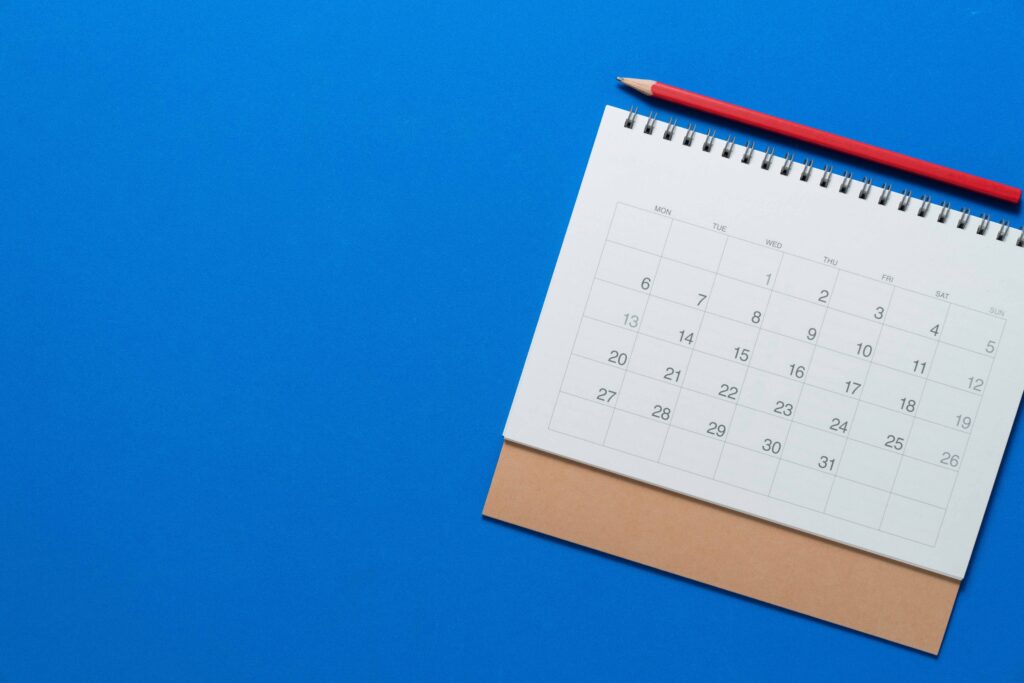 青い背景の前に置かれたカレンダーと鉛筆