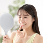 セラミック治療で白くなった歯を鏡でみて嬉しそうな女性