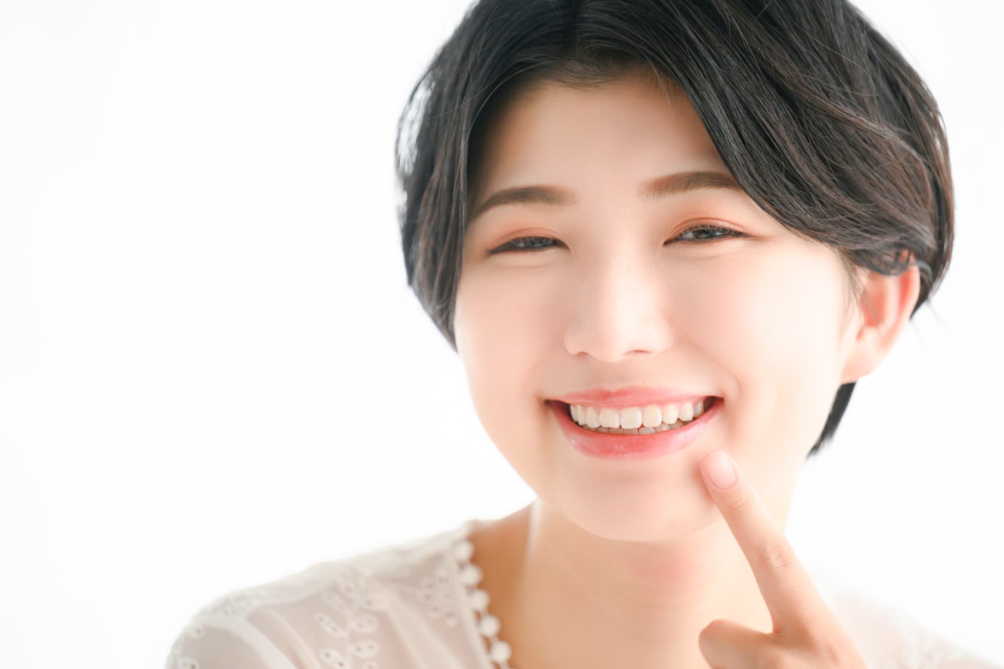 抜歯せずにきれいになった歯を指さす女性