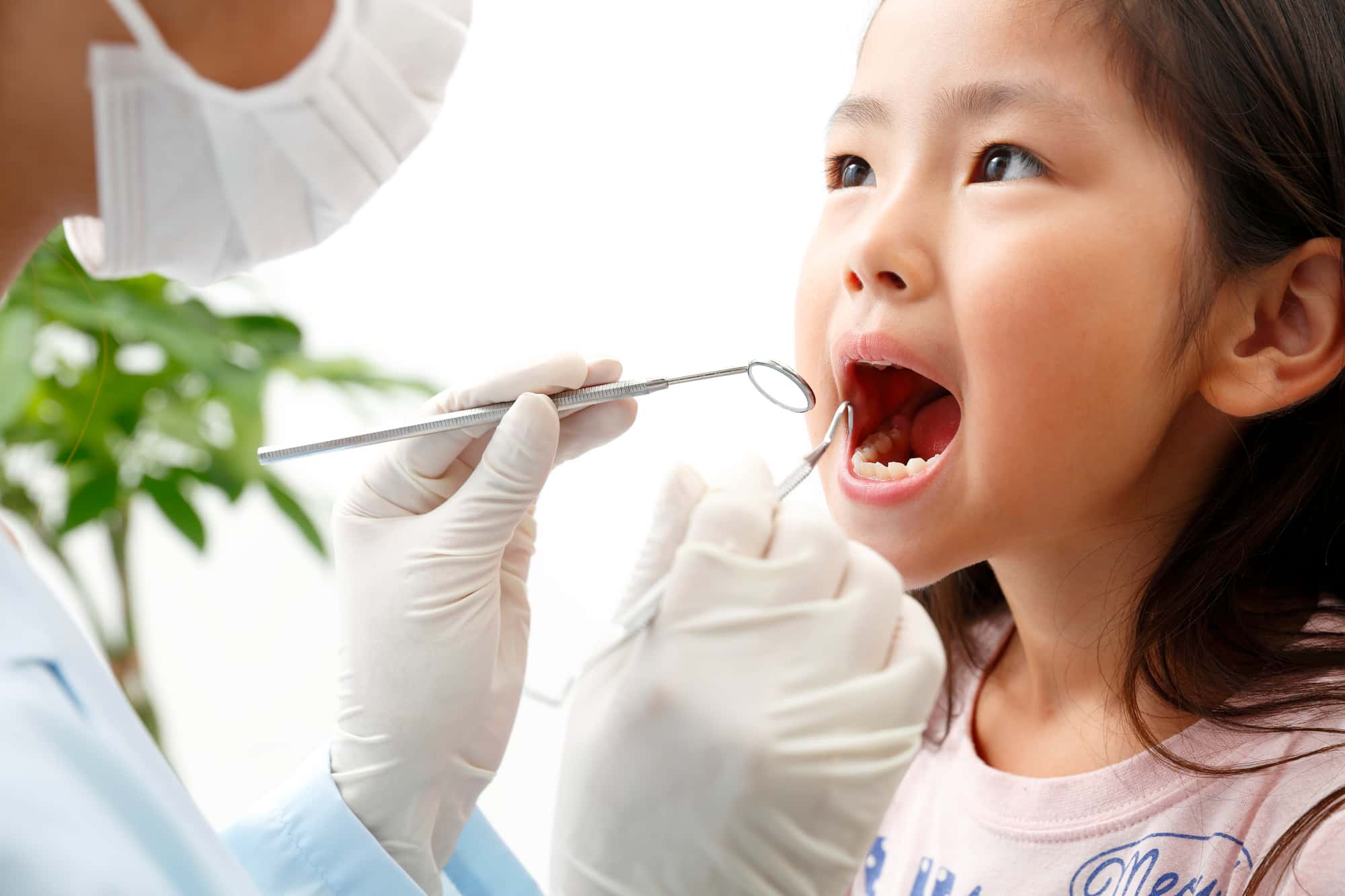 歯科医院でフッ素塗布前に歯のチェックを受ける子ども