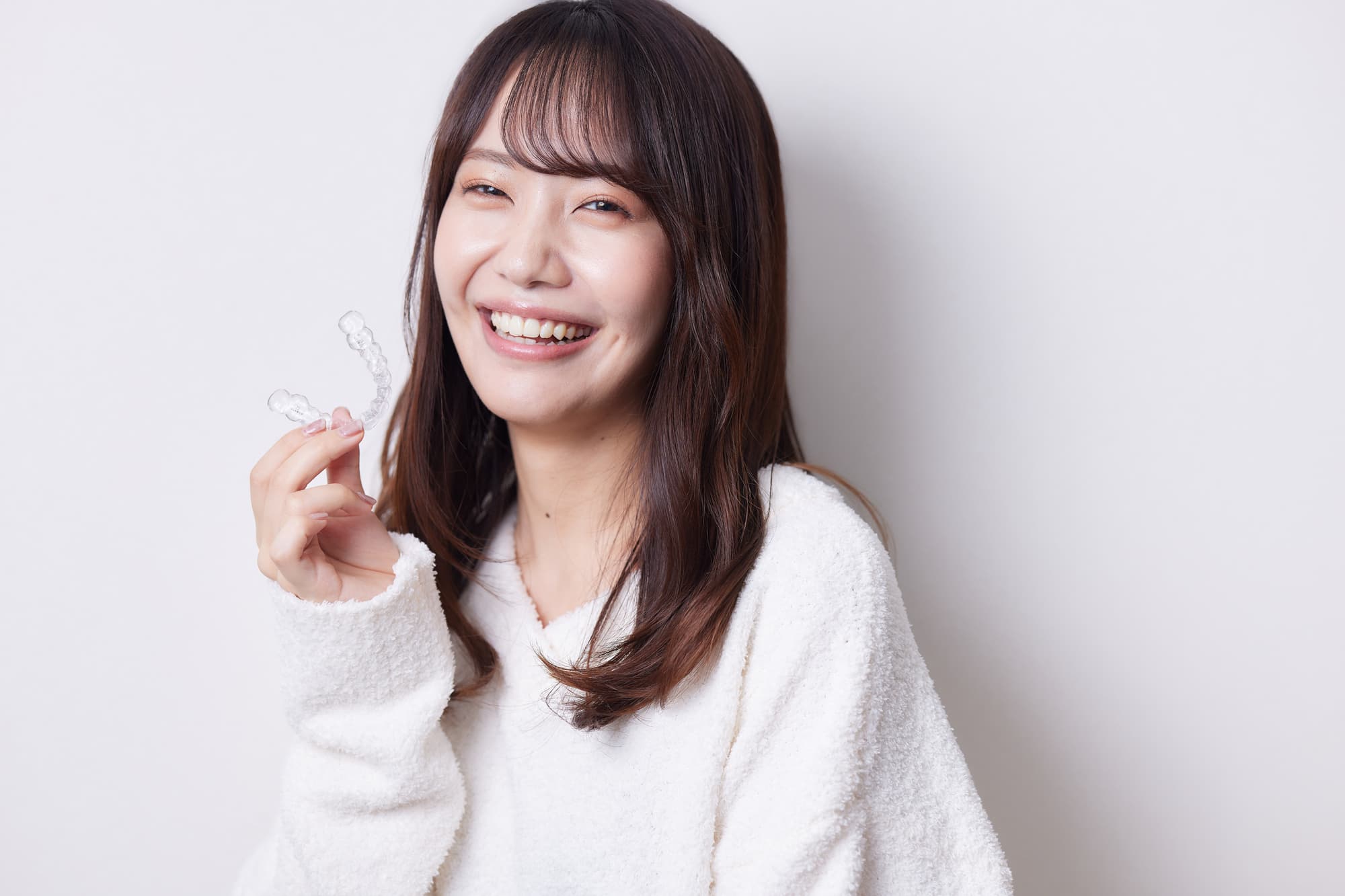 マウスピースを持って笑顔を見せる女性